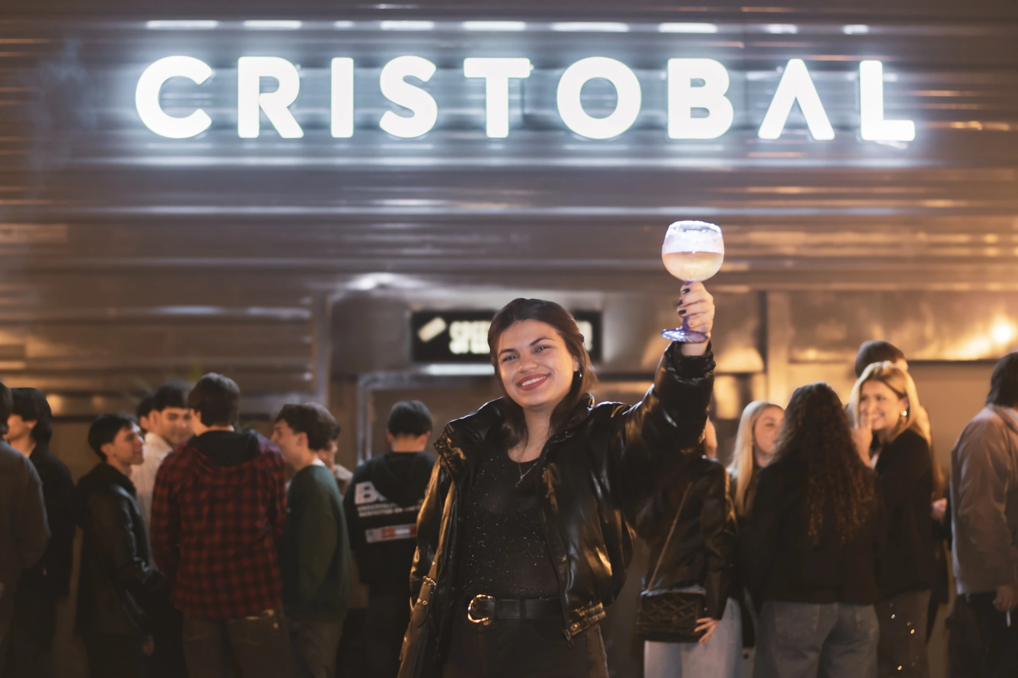 Chica brindando feliz en la entrada de Cristobal Bar