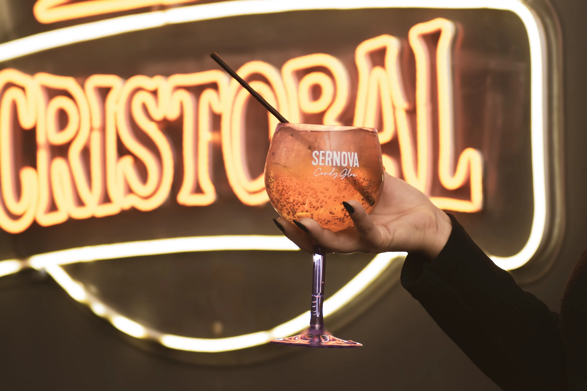 Brindis con la copa frente al cartel de Cristobal Bar